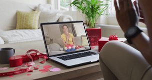 Happy biracial woman opening gift and making valentine's day video call on laptop. valentine's day celebration, lgbtqi,romance and communication technology.