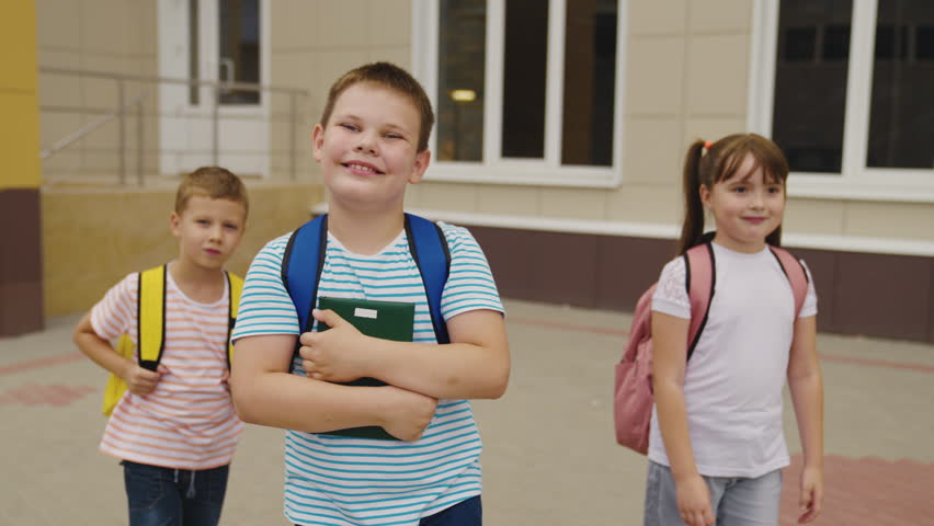 Happy child students walk with textbook their hands smile. group funny children recess walking around school yard. first grader student friend. kid with backpack smile together. school bags children. | Shutterstock HD Video #1099620143