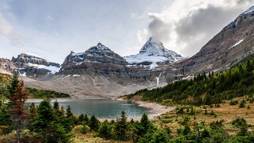 Time lapse of Mount Assiniboine famous with blue sky in autumn forest reflection on Lake Magog at Assiniboine provincial park, BC, Canada
