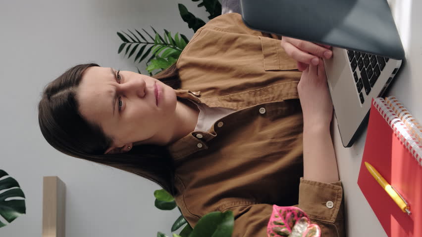 Vertical shot of exhausted upset young female suffering from eye strain, dry eye syndrome, massaging eyelids, tired stressed girl sitting on sofa. Businesswoman feeling fatigue after long laptop use Royalty-Free Stock Footage #1099622613