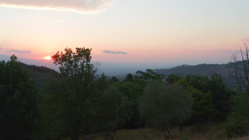 Sunrise Italy Tuscany. Beautiful sun colorful sky early morning over open Italian landscape. Low angle aerial drone flight through green trees
