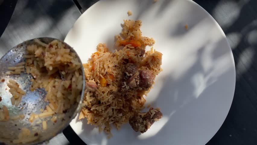 Hot delicious pilaf with rice and chicken decorate with a sprig of fresh cilantro and vegetable salad