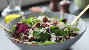 Salad making video 4k. Fresh nutrition salad of beetroot, babyspinat, onions, rukkola, pecan and white soft cheese. Homemade cooking footage.