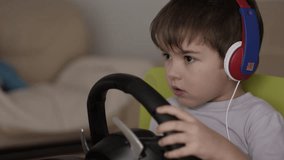 Boy Playing Racing Video Game in Game Console. Child Playing Computer Game in Headphones With Steering Wheel. Gamer With Headset Holding Steering Wheel Playing Video Game. Kid Gambling Addiction.