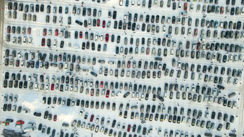 Aerial view of vehicle open market lot with many cars for sale parked and people customers walking in winter