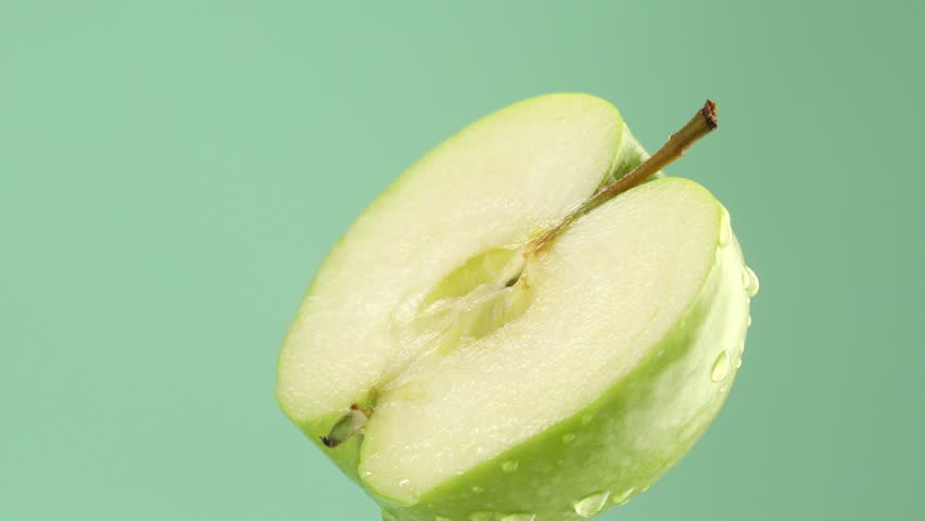 half a green apple with water drops on a green background. fresh fruit close-up. High quality 4k footage - Powered by Shutterstock - Get 15% off with code: PIKWIZARD15