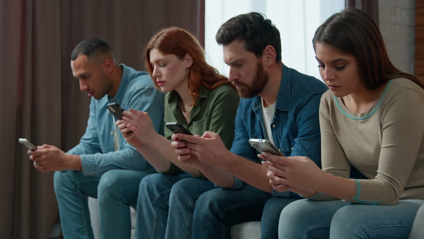 Millennial 30s diverse people sit in line on sofa holding smartphone ignoring friends chatting online in messenger mobile phone addicted women men internet overuse problem modern wireless tech usage  | Shutterstock HD Video #1099633845