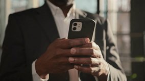 Cropped view male hands touch mobile phone screen typing message unrecognizable african american man adult office user businessman use internet web app close-up cellphone gadget in sun rays sunbeams - Powered by Shutterstock - Get 15% off with code: PIKWIZARD15