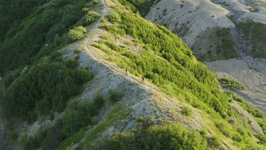 Mountainbikers riding volcanic ridge at Mount St. Helens with bright sunshine, aerial