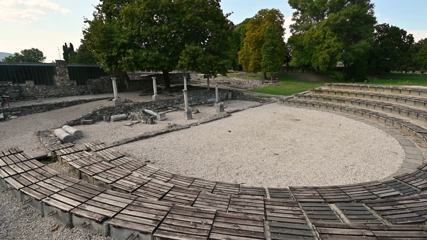 Budapest, Hungary. August 2022. Footage at the Roman archaeological site of Aquincum. The tilt movement shows the amphitheater. Beautiful summer day.