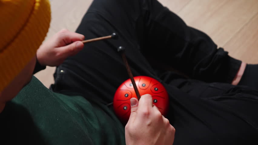 Man playing red tank HAPI drum with sticks. High quality 4k footage