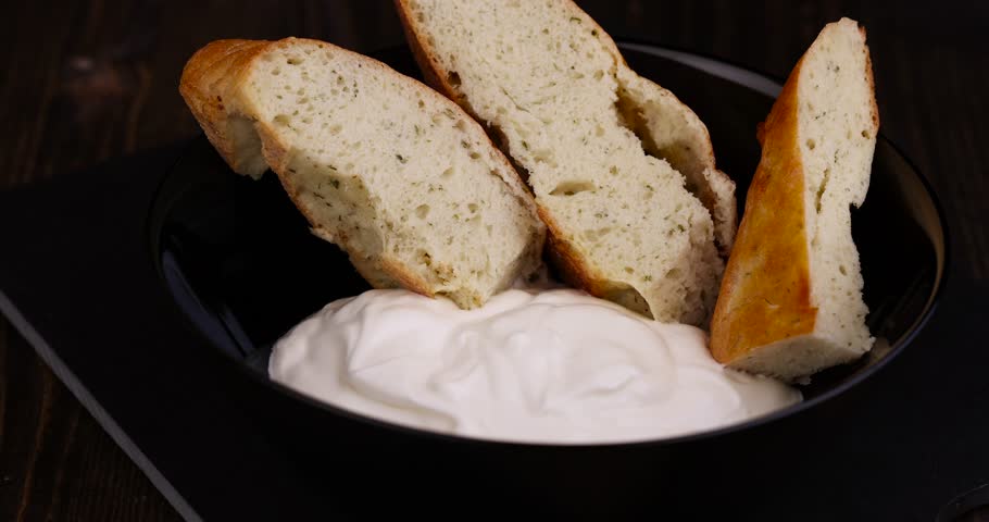 oriental flatbread made of wheat flour with sour cream, parts of oriental fresh flatbread on the table and sour cream from milk