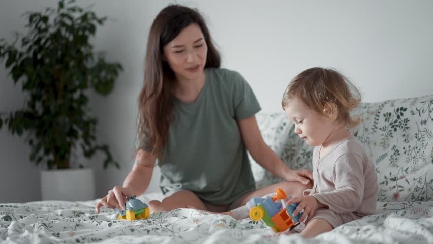 close up young happy smiling asian mother play toy cars with her curly toddler son baby in morning bedroom. Concept of children, baby, parenthood, childhood, life, maternity, motherhood relationship Royalty-Free Stock Footage #1099653903