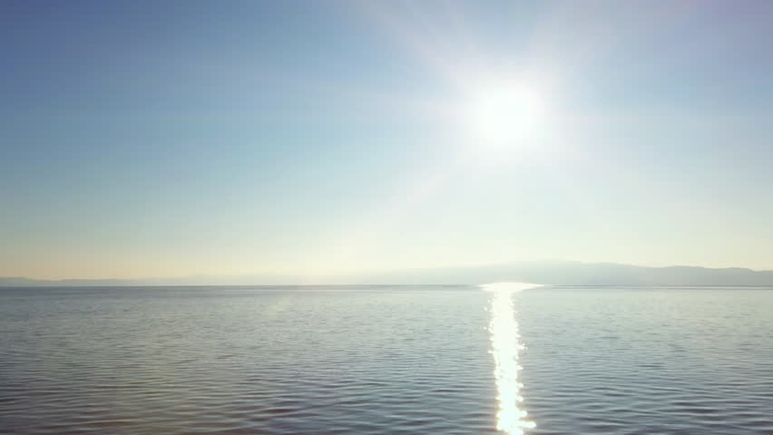 Panoramic view of a lake horizon with sun beams reflecting on the surface
