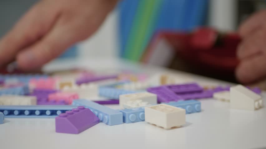Blurred Shooting with an Elderly Person Playing Like a Child with Colorful Small Toy Bricks on the Table.