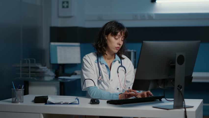 Tired exhausted physician woman working late at night in hospital office analyzing patient disease report on computer typing medical expertise. Stressed doctor planning health care treatment | Shutterstock HD Video #1099659105