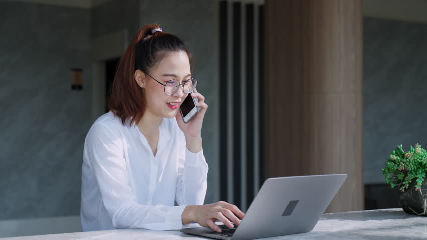 Business woman multitasking female manager worker consultant talking on phone typing on laptop. Businesswoman working with laptop and deal customer. Negotiating online remote conversation. | Shutterstock HD Video #1099669743