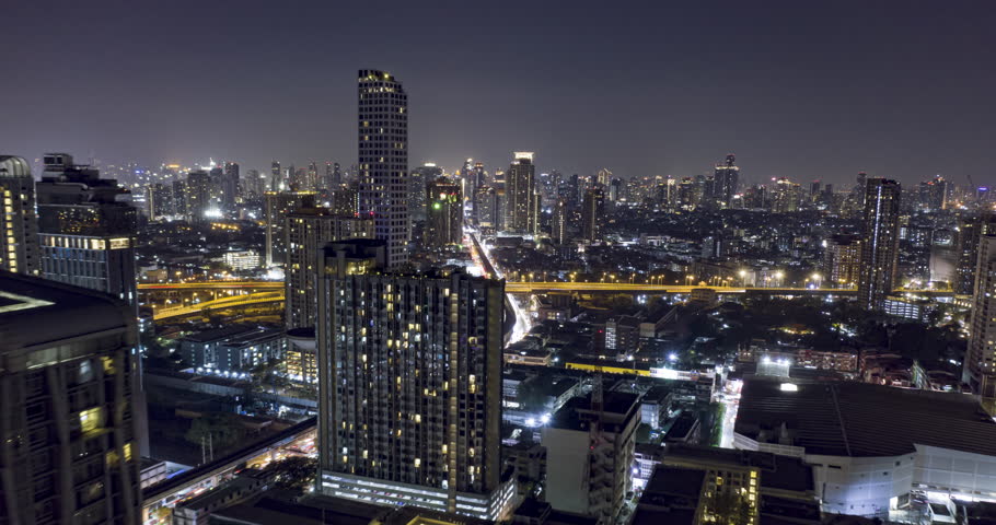 Aerial night illuminated drone flight hyperlapse of Bangkok showing skyline and high rise condominiums in the capital of Thailand with pull back motion. Royalty-Free Stock Footage #1099669897