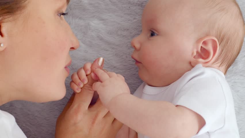 Happy newborn baby with his mother.  Healthy newborn baby in a white t-shirt with mom.   Closeup Faces of the mother and infant baby. Cute  Infant boy and parent, top view.  Slow motion. Happy family | Shutterstock HD Video #1099673565