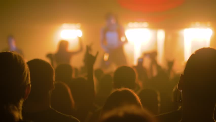 Super slow motion: people crowd partying, raising hands up, showing sign - devil's horns gesture at rock concert in front of stage of nightclub. Nightlife and entertainment concept | Shutterstock HD Video #1099677159