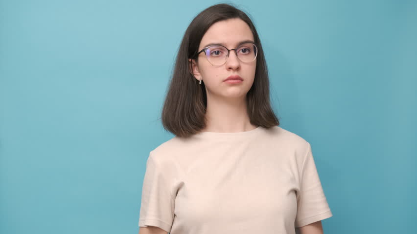 Video portrait of a cheerful student girl hugging, twisting a gray bear toy on a blue background, 4K. Favorite toy. Antistress for adults