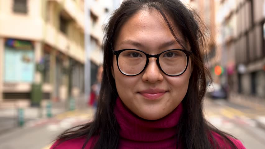 Young asian woman looking on camera in the city