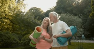 Healthy senior couple with yoga mat in the park