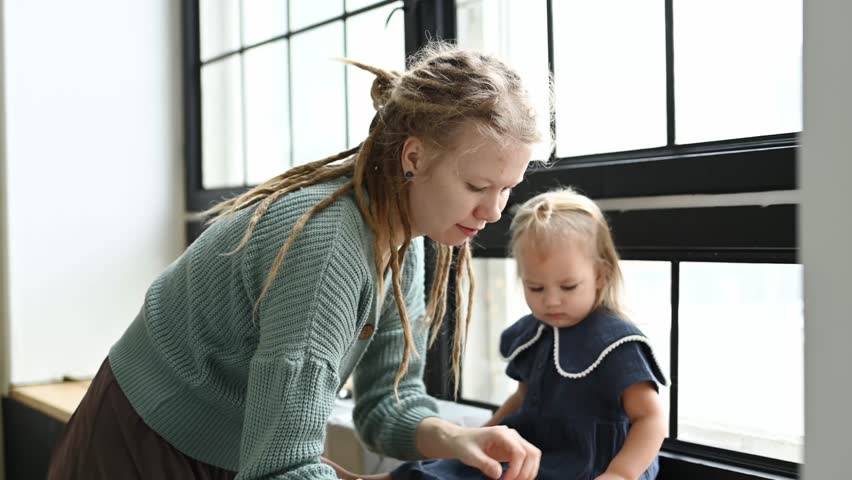 Mom and daughter in the room playing with wooden toys by the big window