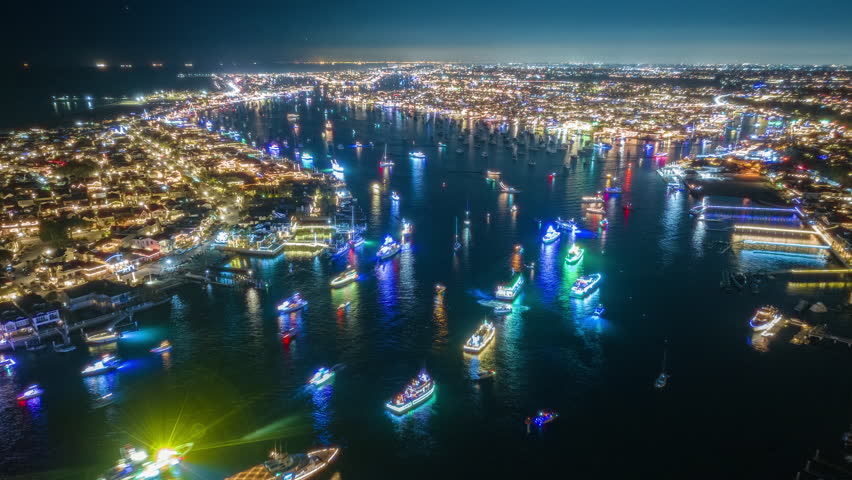 Night hyperlapse of wealthy oceanfront homes, mansions and luxurious lifestyles of rich and famous in Balboa Island and Newport Beach, California. Christmas boat parade with Yachts on holiday vacation