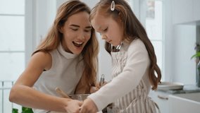 Mom daughter whisking dough indoors closeup. Overjoyed woman little girl making holiday cake at kitchen. Adorable child helping lady cooking. Mother kid baking pastry mixing flour to recipe together - Powered by Shutterstock - Get 15% off with code: PIKWIZARD15