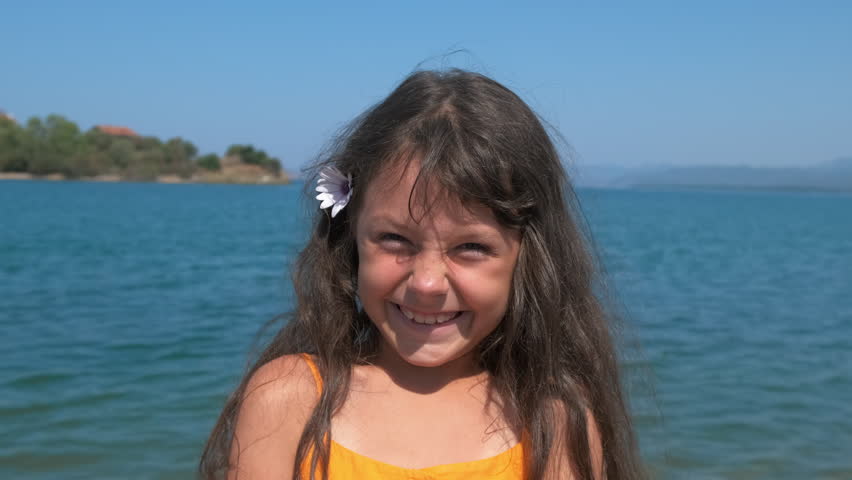 Hold flower in hair on piers. A smiling little girl hold a flower in her hair and pass her time on sunny beach by the blue sea.