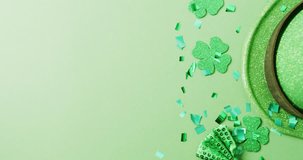 Video of st patrick's green shamrock leaves and hat with copy space on green background. St patrick's day, irish tradition and celebration concept.