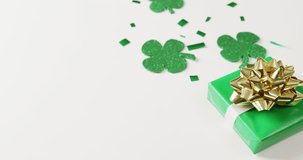 Video of st patrick's shamrock leaves and present with copy space on white background. St patrick's day, irish tradition and celebration concept.