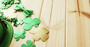 Video of st patrick's green hat, shamrock and bow tie on wooden background. St patrick's day, irish tradition and celebration concept.