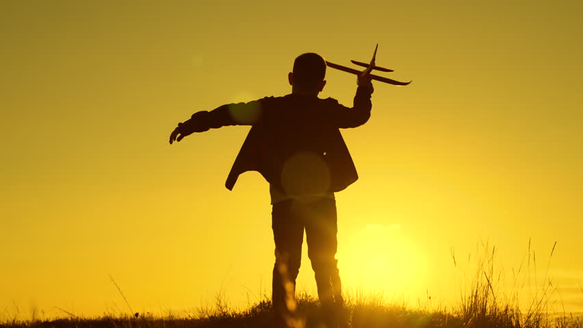 Child boy aviator plays with toy plane in park in sunset. Child wants to become an astronaut. Children play with toy plane. Teenager dreams of flying, becoming pilot. Boy dreams of flying, traveling | Shutterstock HD Video #1099690437