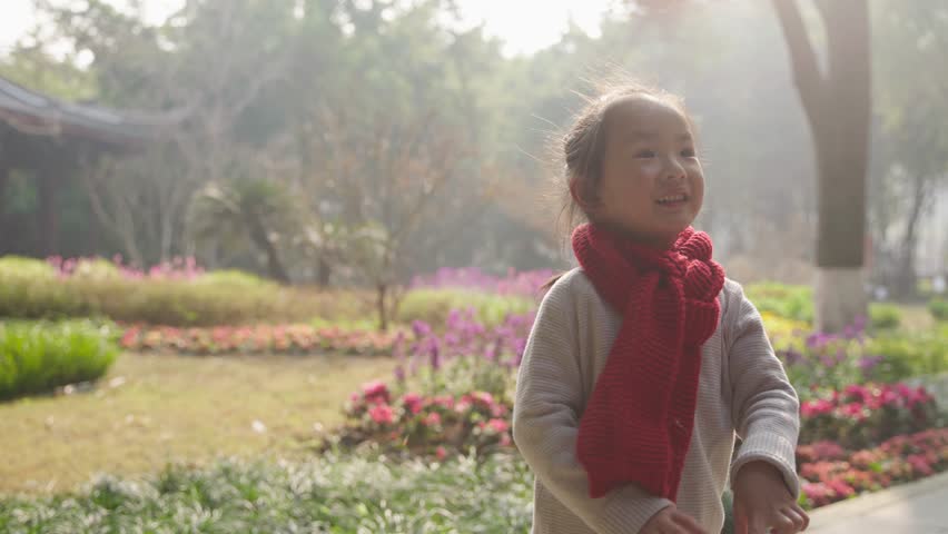 lovely asian little girl smile laugh in the park during chines new year wear red scarf