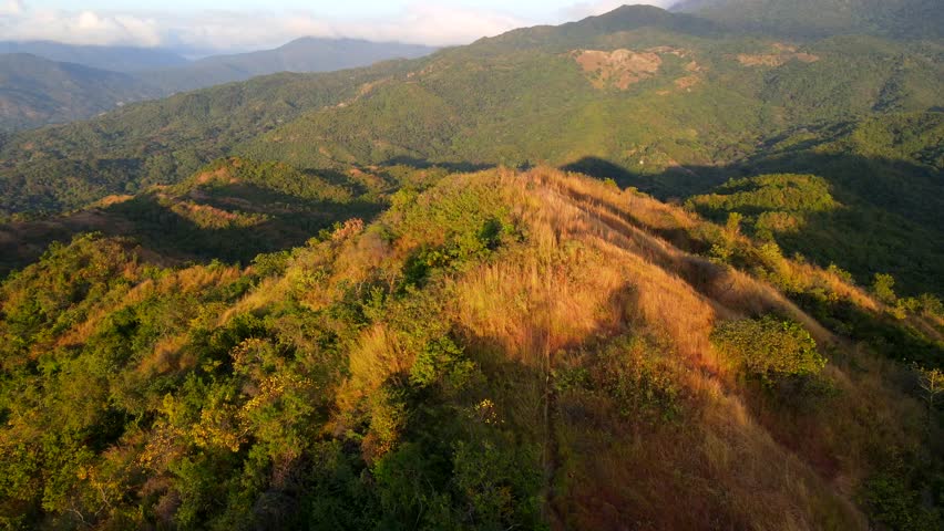 Aerial shot drone wide shot of top of mountain in orbit with sunset behind