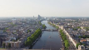 Inscription on video. Amsterdam, Netherlands. Flying over the city rooftops. Amstel River. Multicolored text appears and disappears, Aerial View