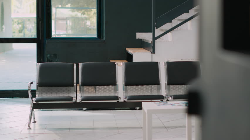 Hospital waiting area in modern healthcare clinic, empty reception lobby filled with chairs and healthcare leaflets. Waiting area corridor at health center, recovery appointments and clinical exam. | Shutterstock HD Video #1099702849