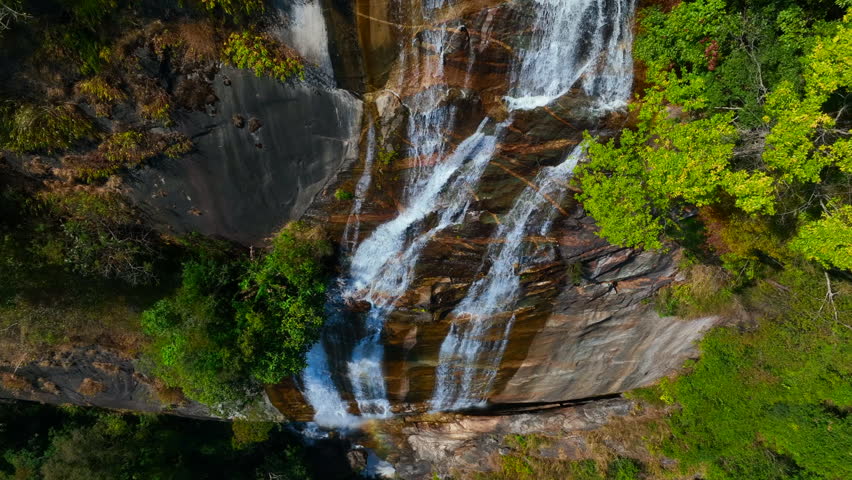 Wide aerial view of waterfall flowing in the depths of the forest. Beautifu large waterfall in the forest. Natural landscape, deep green forest and plants surrounded. Water flow from stones.