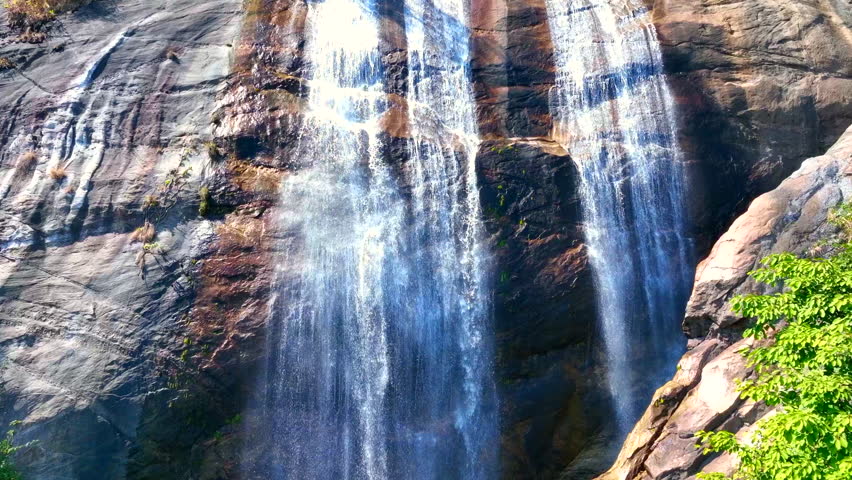 Wide aerial view of waterfall flowing in the depths of the forest. Beautifu large waterfall in the forest. Natural landscape, deep green forest and plants surrounded. Water flow from stones.