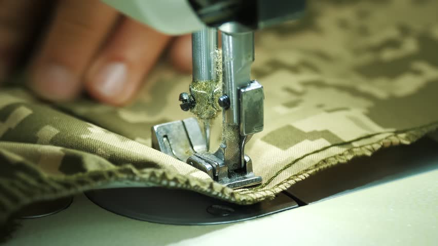 sewing. close-up. seamstress sews khaki, dark green fabric on sewing machine. Sewing Machine Needle in Motion. Working process at clothing manufacturing factory. Royalty-Free Stock Footage #1099713089