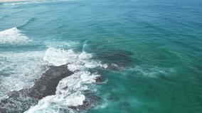 Surfers and rocks make for a stunning drone video! The camera glides through the air, capturing the surfers from unique angles.