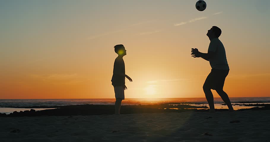 Father and Son playing football, family fun outdoors players in soccer in dynamic action have fun playing football in the beach, summer day under sunlight. | Shutterstock HD Video #1099716199