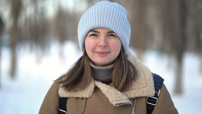 Portrait of a woman applying facial moisturizer cream in winter