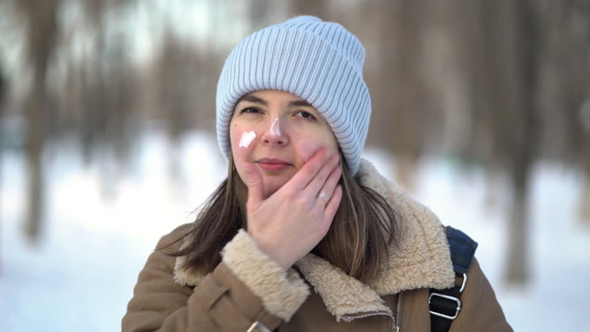 Portrait of a woman applying facial moisturizer cream in winter Royalty-Free Stock Footage #1099717331