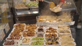 This video shows an asian food stand cook preparing plated carry out food for customers.