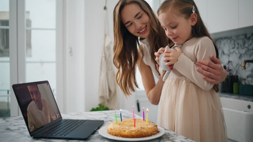 Birthday girl blowing candles at kitchen closeup. Smiling woman clapping hands feeling happy at cozy interior. Family celebrating child anniversary at laptop virtual chat. Mother greeting daughter - Powered by Shutterstock - Get 15% off with code: PIKWIZARD15