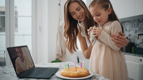 Birthday girl blowing candles at kitchen closeup. Smiling woman clapping hands feeling happy at cozy interior. Family celebrating child anniversary at laptop virtual chat. Mother greeting daughter - Powered by Shutterstock - Get 15% off with code: PIKWIZARD15