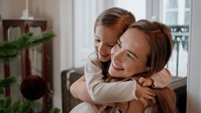 Tender mother daughter hug at New Year tree place portrait. Smiling woman bonding to cute baby at cozy home close up. Sweet family embracing together at Christmas house. Celebration holidays concept - Powered by Shutterstock - Get 15% off with code: PIKWIZARD15